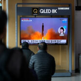 People watch a TV screen showing reporting about North Korea's missile with file footage.