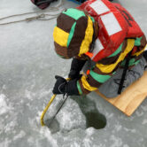 A researcher saws into the frozen surface of Lake Huron's Saginaw Bay.