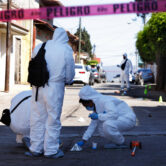 Investigators comb the site of a gun battle in Mexico's Michoacan state.