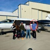 Five people standing in front of an airplane
