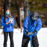 A man pushes a probe into the Sierra Nevada snowpack.