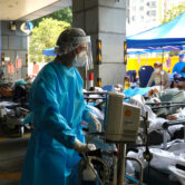 Patients in hospital beds wait in a temporary holding area in Hong Kong.