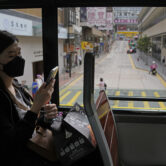 A woman wearing a face mask rides on a tram in Hong Kong.