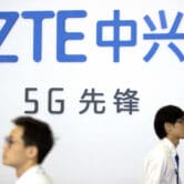 Visitors walk past a display for ZTE at the PT Expo in Beijing in 2018.