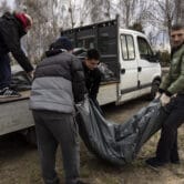 Cemetery workers lift three corpses of civilians killed in Bucha, Ukraine.