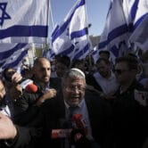Itamar Ben-Gvir, surrounded by right-wing activists with Israeli flags, speaks to the media .