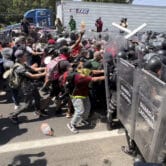 Migrants break through a line of National Guard officers trying to block them in Mexico.
