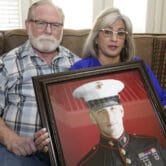 Joey and Paula Reed pose for a photo with a portrait of their son Trevor Reed in their home.