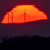 Wind turbines stand in front of the rising sun in Frankfurt, Germany.