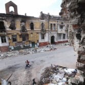 Children walk among buildings destroyed during fighting in Mariupol.