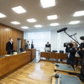Judges stand in front of people holding cameras in a court in Kasseel, Germany.