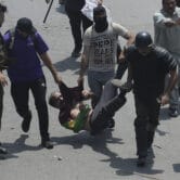 Police officers detain a person as clashes broke out during a protest march.