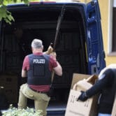 German police officers carry several stabbing weapons and spears from a suspect's home.