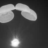 A SpaceX Dragon capsule uses parachutes as it descends in the Gulf of Mexico.