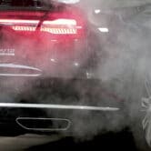 An Audi car is surrounded by exhaust gases as it is parked with a running engine.