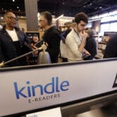 Customers stand near a Kindle display at an Amazon retail store.