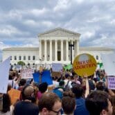 Protesters hold signs outside Supreme Court