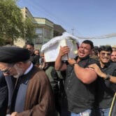 People carry a coffin containing a victim of an artillery strike.