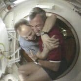Terrence Wilcutt and Anatoly Solovyev hug in space.