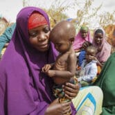 A woman holds her malnourished infant child at a camp in Somalia.