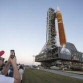 People take photos of a NASA rocket at the Kennedy Space Center.