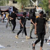 Armed fighters walk along a street in Baghdad.