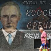 A man passes by graffiti depicting Vladimir Putin in Serbia.