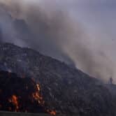 A person picks through trash as a fire rages at a landfill in India.