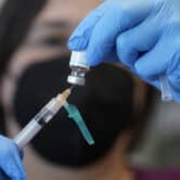 A nurse inserts a syringe into a vial of monkeypox vaccine.