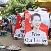Protesters walk through a market with posters in Myanmar.