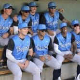 Minor league baseball players pose for a photo in a dugout before a game.