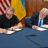 Two men sign papers