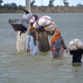 A displaced family wades through a flooded area in Pakistan.