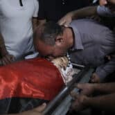 The father of a 7-year-old Palestinian boy kisses his dead body at a hospital in the West Bank.