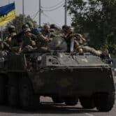 Ukrainian troops ride on top of a tank