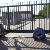 A man sits outside the gate of an overcrowded asylum-seekers center in the Netherlands.