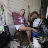 A woman sits near belongings from her mobile home, which was flooded by Hurricane Ian.