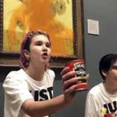 A protester holds a can of tomato soup in front of a Van Gogh painting after throwing more soup at it.