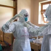 Doctors put on protective equipment in Uganda.