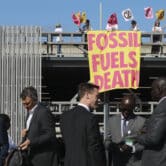 Climate activists hold a sign that reads "FOSSIL FUEL DEATHS" in South Africa.
