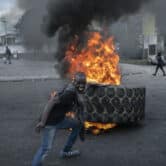 A protester adds a tire to a burning barricade during a protest in Haiti.