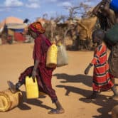 A Somali woman and children carry water at a camp for displaced people.