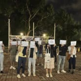 Protesters hold up blank white papers during a commemoration for victims of a fire in Hong Kong.