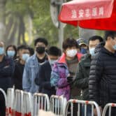 People wearing face masks stand in line at a coronavirus testing site in Beijing.