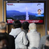 A TV screen shows a news program reporting about a North Korean missile launch with file footage.
