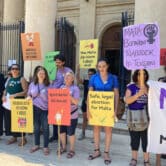 Pro-choice activists hold signs while rallying outside a courthouse in Malta.