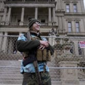 Timothy Teagan stands with a rifle outside the state capitol in Lansing, Michigan.