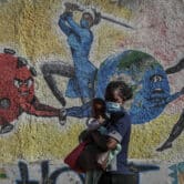 A woman and child walk past an informational mural portraying the global battle against Covid-19 in Kenya.