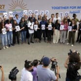 Youth climate activists hold signs that read "from COP27 to G20 fight for 1.5" at a U.N. climate summit in Egypt.