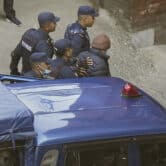 Nepalese police escort Charles Sobhraj into a building.
